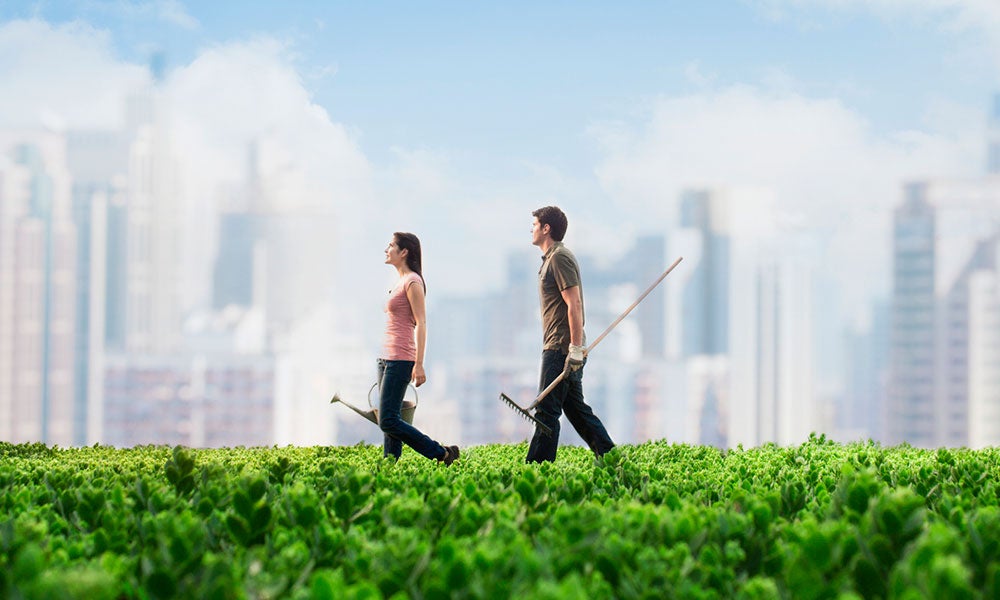 Two people walking in a field with cityscape in background